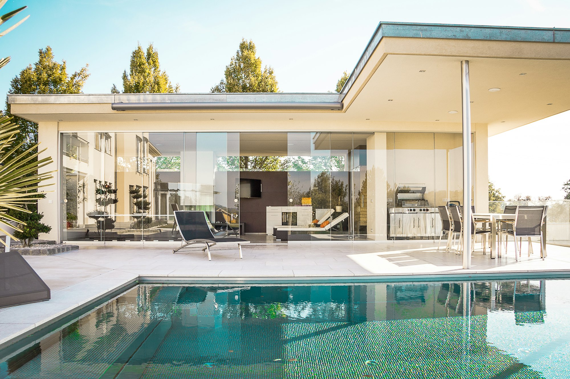 Casa de una planta con porche acristalado y la piscina en primer plano